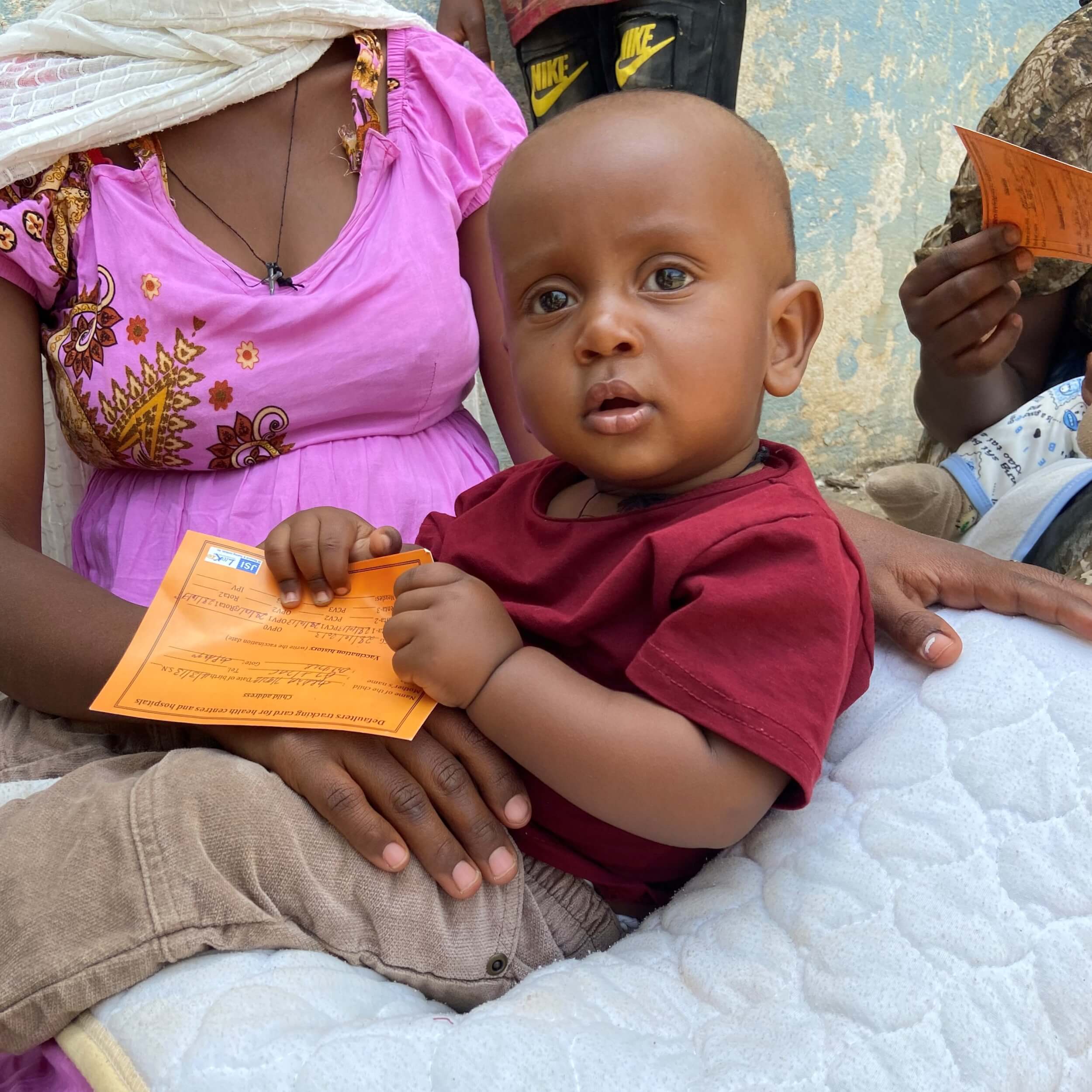 Haileab sits on his mother's lap waiting for a vaccines at a medical clinic